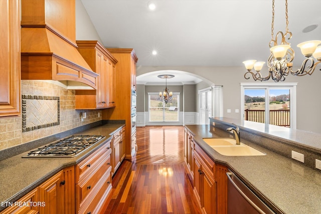 kitchen featuring arched walkways, dark countertops, an inviting chandelier, appliances with stainless steel finishes, and a sink