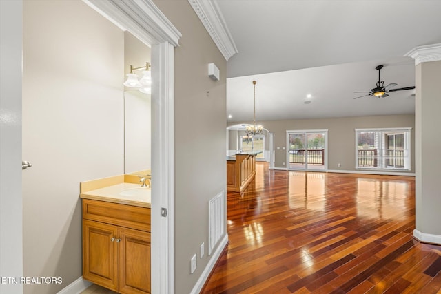 interior space featuring crown molding, visible vents, a sink, and wood finished floors