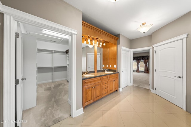 bathroom featuring tile patterned flooring, a sink, baseboards, and double vanity