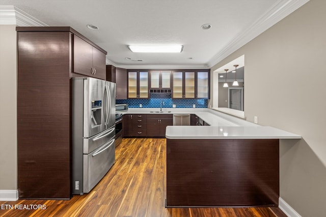 kitchen with glass insert cabinets, dark wood-style flooring, a peninsula, stainless steel appliances, and a sink