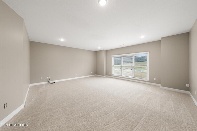 spare room with baseboards, recessed lighting, and light colored carpet