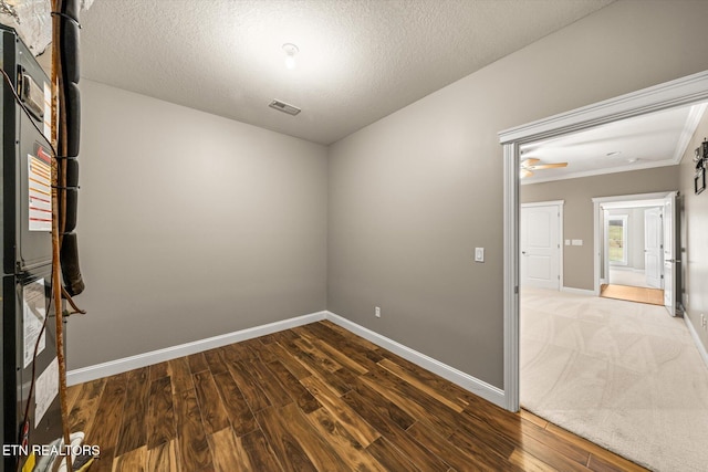 spare room with visible vents, a textured ceiling, baseboards, and wood finished floors