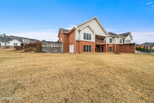 back of house with brick siding and a lawn