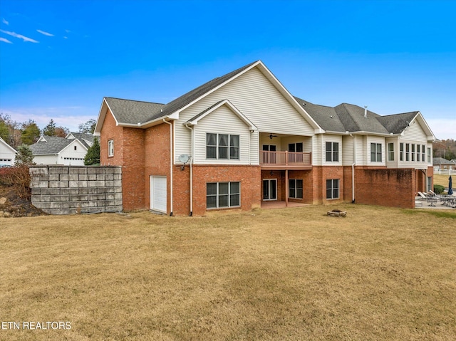 back of house with an outdoor fire pit, brick siding, ceiling fan, and a lawn