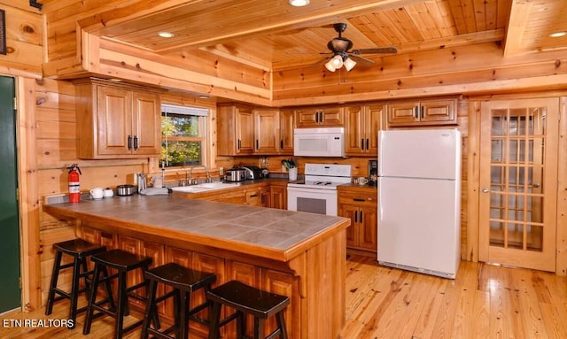 kitchen featuring tile counters, white appliances, brown cabinets, and a peninsula