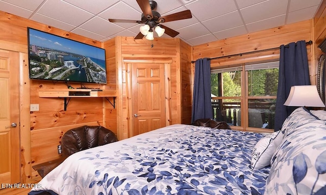 bedroom featuring a paneled ceiling and wooden walls