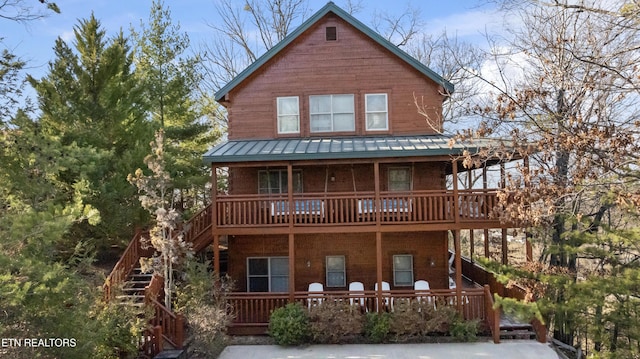 chalet / cabin with stairs, metal roof, a porch, and a standing seam roof