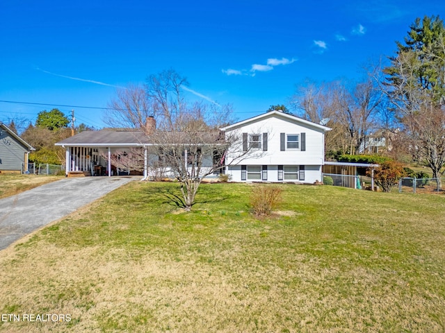 tri-level home with a carport, a front lawn, fence, and driveway