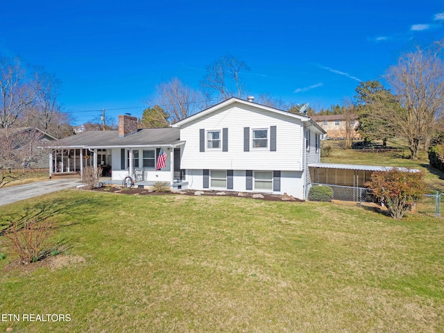 split level home with driveway, a chimney, a front lawn, and fence