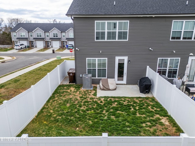 rear view of house featuring a patio, a fenced backyard, roof with shingles, a lawn, and a residential view