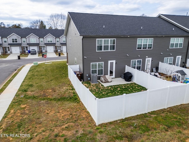 rear view of property with a yard, a fenced backyard, a residential view, and central air condition unit