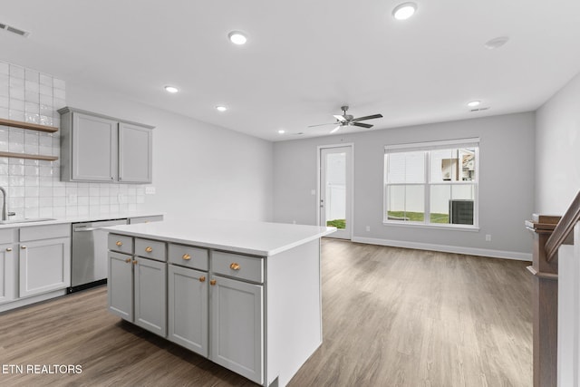 kitchen with gray cabinetry, visible vents, light countertops, stainless steel dishwasher, and tasteful backsplash