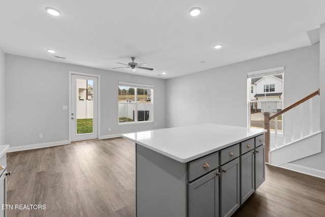 kitchen with baseboards, a kitchen island, dark wood-style flooring, gray cabinets, and recessed lighting