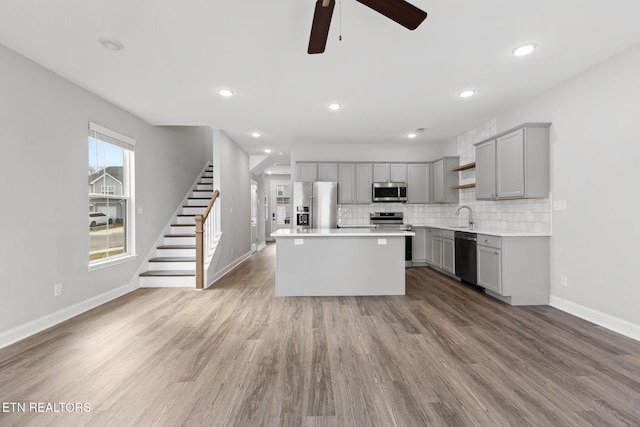 kitchen with appliances with stainless steel finishes, gray cabinets, a sink, and open shelves