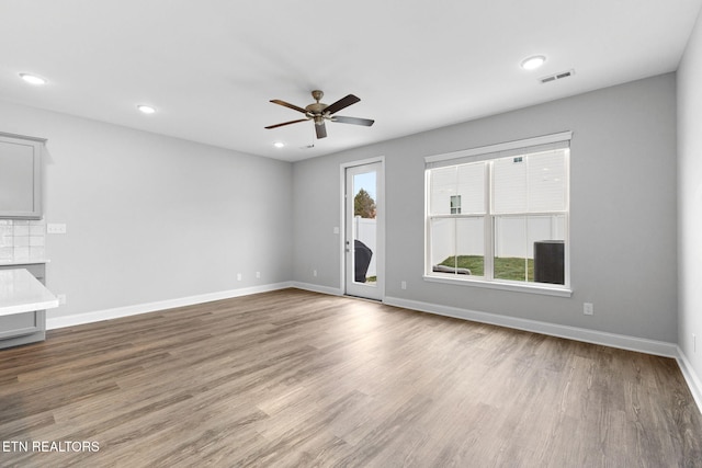 unfurnished living room featuring baseboards, visible vents, a ceiling fan, wood finished floors, and recessed lighting