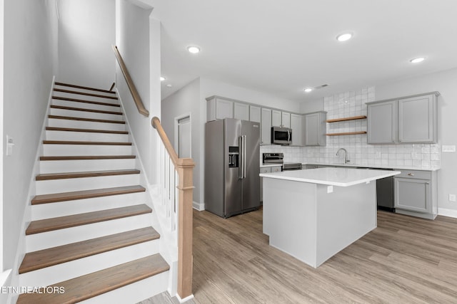 kitchen with light wood finished floors, gray cabinets, stainless steel appliances, and a sink