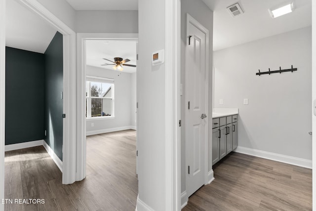 hallway featuring dark wood finished floors, visible vents, and baseboards