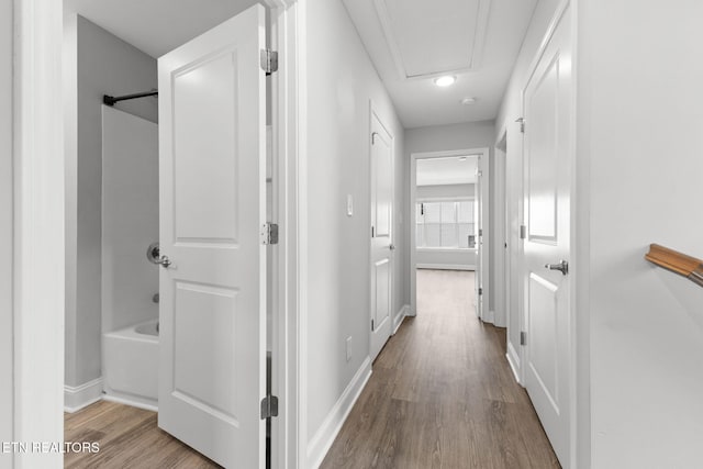 corridor with baseboards and wood finished floors