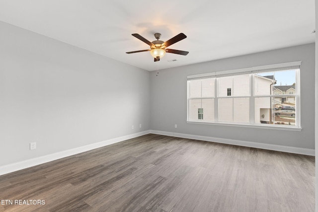 empty room featuring ceiling fan, baseboards, and wood finished floors