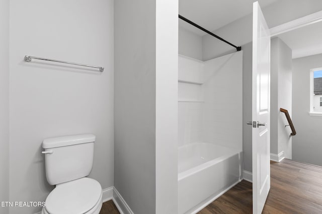 full bath featuring washtub / shower combination, wood finished floors, toilet, and baseboards