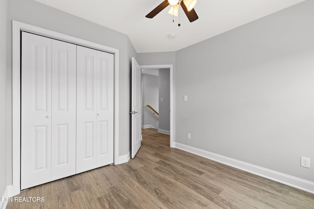 unfurnished bedroom with a ceiling fan, a closet, baseboards, and wood finished floors