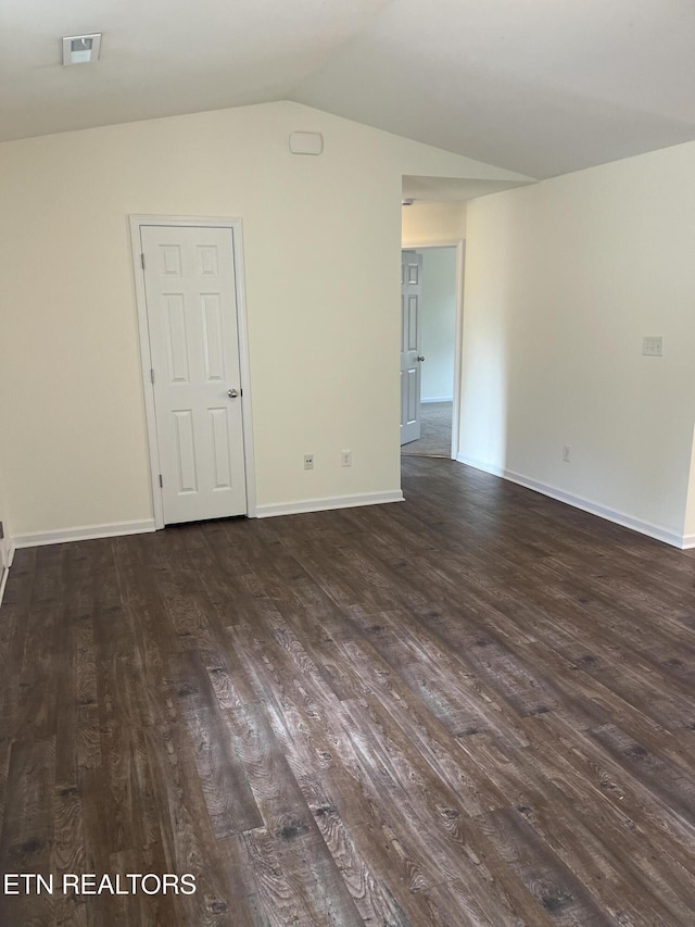 spare room with baseboards, lofted ceiling, visible vents, and dark wood-style flooring