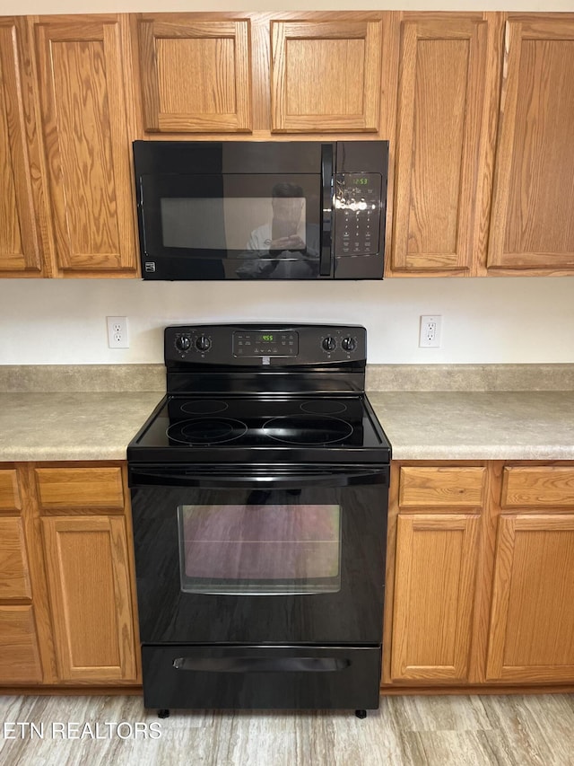 kitchen with black appliances, light wood-style flooring, and light countertops