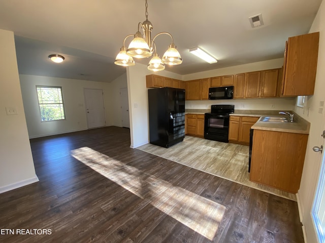 kitchen with light wood finished floors, open floor plan, light countertops, black appliances, and a sink