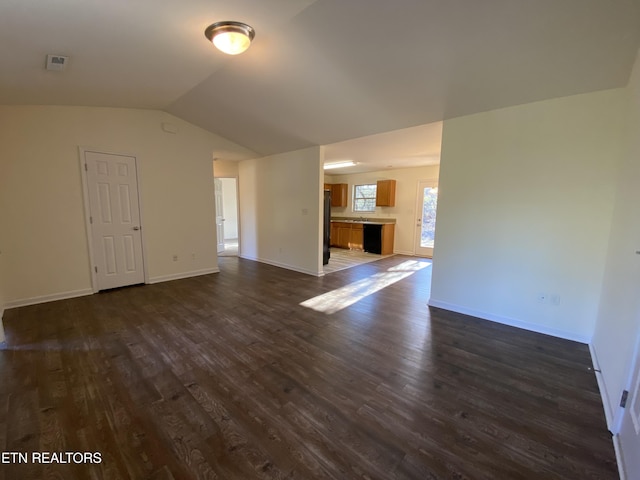 unfurnished living room featuring lofted ceiling, dark wood-style floors, and baseboards