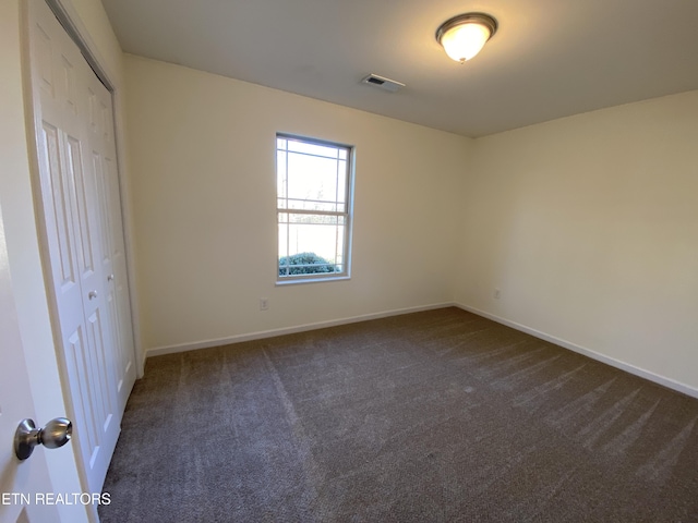 unfurnished bedroom featuring a closet, baseboards, visible vents, and dark carpet