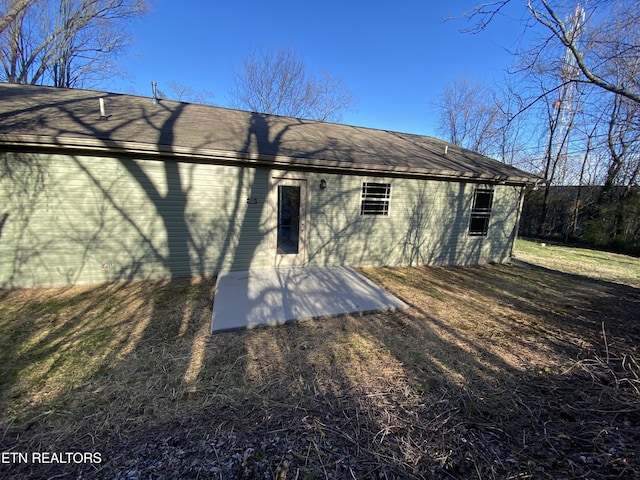 back of house featuring a patio area and roof with shingles