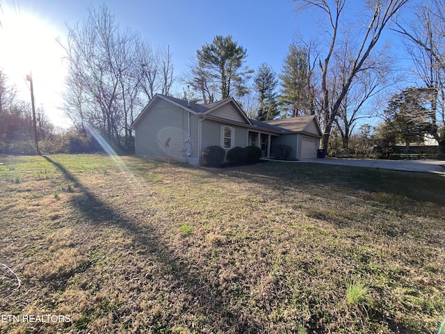 view of side of home featuring a yard, driveway, and a garage