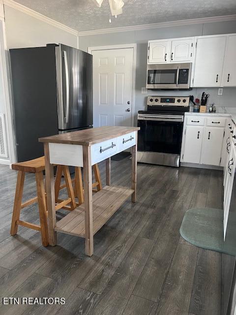 kitchen featuring dark wood-style floors, appliances with stainless steel finishes, and crown molding