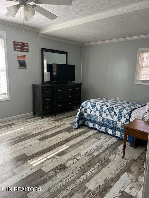 bedroom featuring a ceiling fan, light wood-type flooring, crown molding, and a textured ceiling