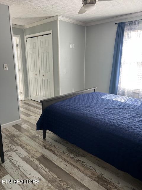 bedroom with ceiling fan, crown molding, a textured ceiling, and wood finished floors