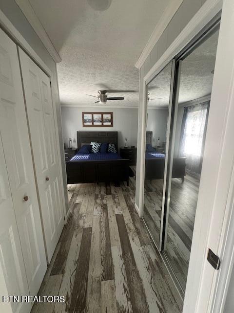 hall with a textured ceiling, crown molding, and wood finished floors