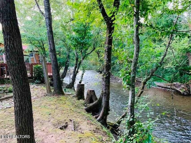 property view of water with fence and a wooded view