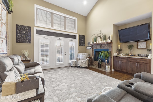 living area with a fireplace, high vaulted ceiling, and dark wood finished floors