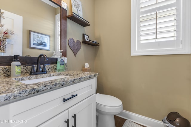 bathroom featuring toilet, vanity, and baseboards