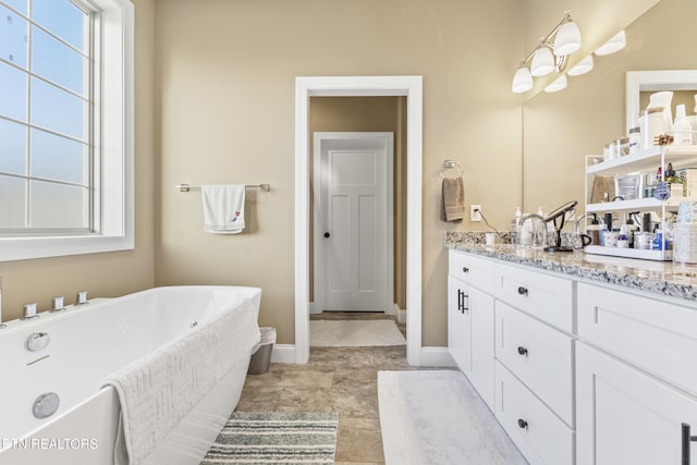 full bath with a wealth of natural light, a soaking tub, vanity, and baseboards