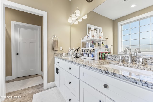 full bath featuring double vanity, baseboards, and a sink