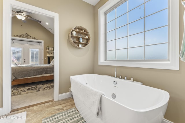 ensuite bathroom featuring baseboards, lofted ceiling, ensuite bathroom, french doors, and a freestanding tub