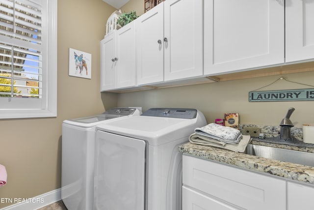 laundry room with baseboards, cabinet space, a sink, and washing machine and clothes dryer