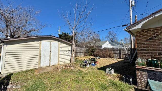 view of yard with an outbuilding, a storage unit, and fence