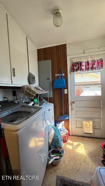 laundry room featuring washer and dryer, cabinet space, and wooden walls