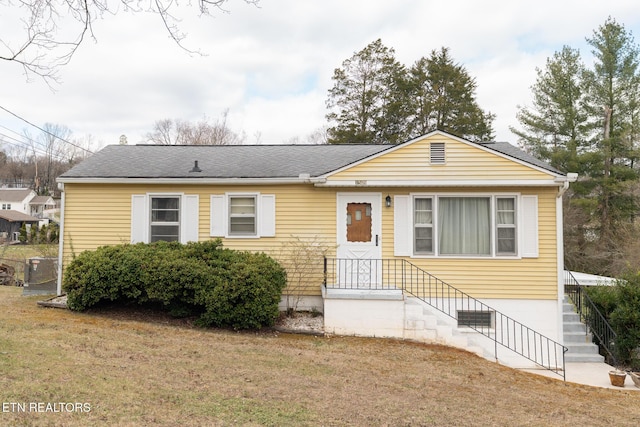 view of front of property featuring a front lawn and roof with shingles