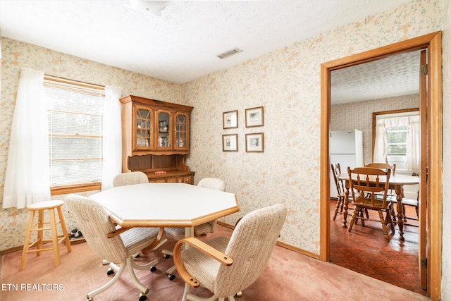 dining area with visible vents, a textured ceiling, baseboards, and wallpapered walls