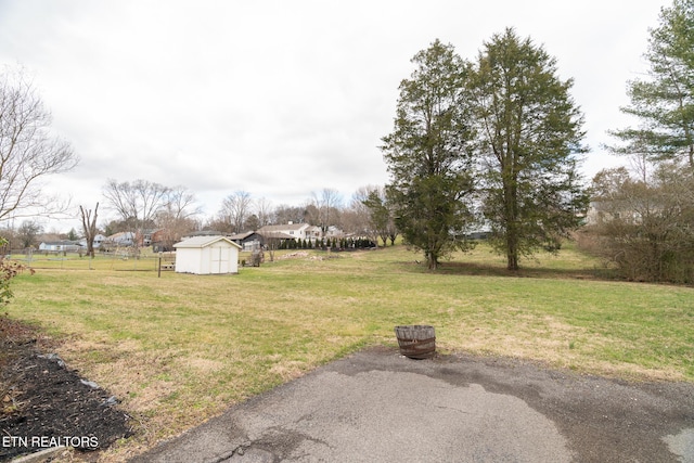 view of yard with an outbuilding, fence, and a storage shed