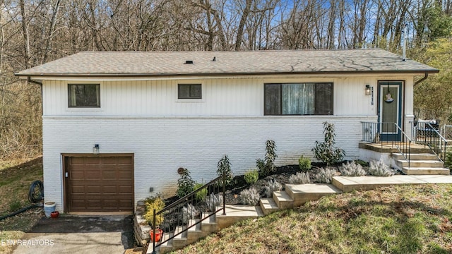 view of front facade with an attached garage, driveway, and brick siding