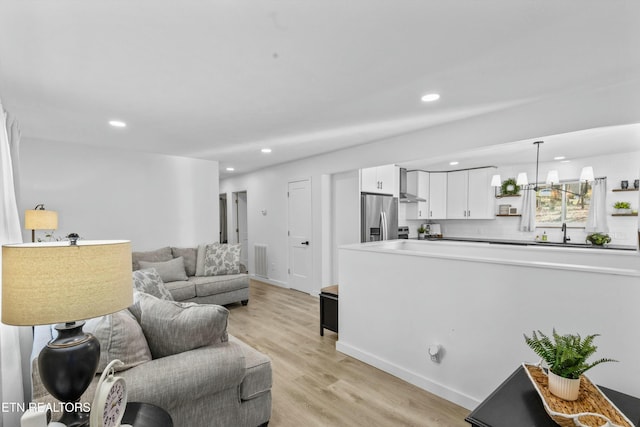 living area with a notable chandelier, recessed lighting, visible vents, light wood-type flooring, and baseboards